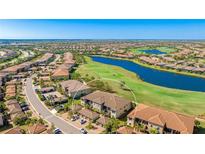 Expansive aerial view overlooking the condo community, scenic golf course, and serene lake at 13719 Messina Loop # 101, Lakewood Ranch, FL 34211