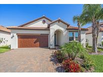 Beautiful single-story home with a tile roof, paver driveway, and lush tropical landscaping at 17216 Star Banks St, Wimauma, FL 33598