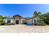 Stunning exterior of home with stone accents, lush landscaping, and brick driveway at 22209 Deer Pointe Xing, Bradenton, FL 34202