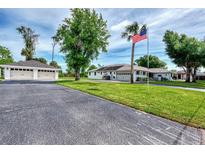 Spacious, well-maintained property featuring a lush lawn, mature trees, a detached garage, and an American flag at 3514 Laslo Ave, North Port, FL 34287