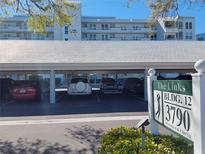 Image shows covered parking at The Links condos, building 12, with lush landscaping and signage at 3790 Pinebrook Cir # 103, Bradenton, FL 34209