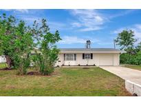 Charming one-story home with a well-maintained lawn, blue sky and lush landscaping at 610 Cumberland Rd, Venice, FL 34293