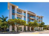 Modern condo building with glass balconies, wood and white accents and lush landscaping at 635 S Orange Ave # 404, Sarasota, FL 34236