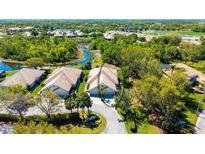An aerial view of a home with a tile roof, tropical landscaping, and a serene waterway in the background at 7004 Old Tabby Cir, Lakewood Ranch, FL 34202