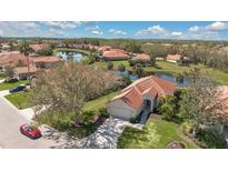 Stunning aerial view of a home with a red tile roof, lush landscaping, and a scenic lake backdrop at 730 Foggy Morn Ln, Bradenton, FL 34212