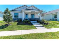 Charming single-story home with a manicured lawn, stone accents, and welcoming front porch with outdoor seating at 7712 Saloon Ln, Sarasota, FL 34240