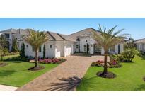 Beautiful single-story home with manicured lawn, brick driveway, and mature palm trees at 7977 Bowspirit Way, Lakewood Ranch, FL 34202
