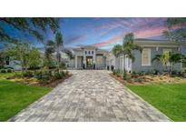 Stately stucco home with a paver drive, manicured landscaping, and a three-car garage at 8348 Catamaran Cir, Lakewood Ranch, FL 34202
