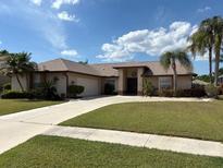 Charming single-story home with a well-manicured lawn and mature palm trees at 4906 Peridia E Blvd, Bradenton, FL 34203