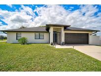 Well-maintained single-story home with a manicured lawn, dark garage door, and decorative plants at 7251 Sunnybrook Blvd, Englewood, FL 34224