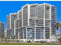 Modern condominium featuring a striking architectural design, glass balconies, and views of palm trees at 1155 N Gulfstream Ave # 708, Sarasota, FL 34236