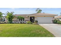 Charming single-story home with well-maintained lawn, lush landscaping, and attached two-car garage at 128 Da Vinci Dr, Nokomis, FL 34275