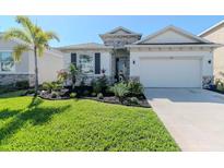 Charming single-Gathering home featuring lush green grass, beautiful landscaping, and a two-car garage at 5277 Grove Mill Loop, Bradenton, FL 34211