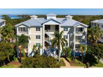 Three-story condo building with balconies, painted in soft yellows and blues, surrounded by palm trees and lush greenery at 7730 34Th W Ave # 103, Bradenton, FL 34209