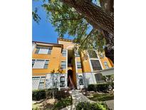 Inviting mustard colored condo building with mature trees and tidy landscaping on a bright, sunny day at 8351 38Th Street E Cir # 302, Sarasota, FL 34243