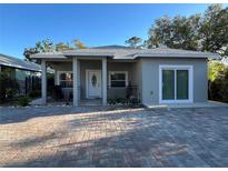 Charming home with gray exterior, covered porch, decorative door and brick paved driveway at 1534 25Th St, Sarasota, FL 34234