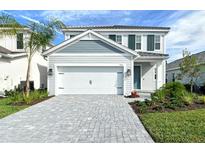 Charming two-story home with a neatly landscaped yard and a paver driveway leading to a two-car garage at 2616 Star Apple Way, Sarasota, FL 34240