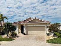 Inviting single-story home featuring a clay tile roof, paver driveway, and lush, mature landscaping at 2160 Chenille Ct, Venice, FL 34292