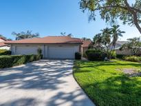 Inviting single-story home with a well-manicured lawn and mature trees with a brick roof and a long concrete driveway at 3922 Wilshire Cir # 177, Sarasota, FL 34238