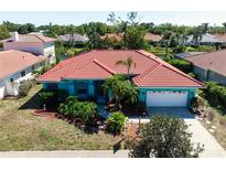 Aerial view of a teal home featuring a red tile roof, landscaped yard, and a private driveway at 4464 Mcintosh Lake Ave, Sarasota, FL 34233