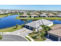 Beautiful aerial view of a modern home surrounded by a lake, landscaped yard, and a gray tile roof at 5311 White Sand Cv, Bradenton, FL 34211