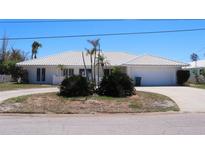 Single story home featuring a white tiled roof, circular driveway, and tidy landscaping at 618 Gladstone Ln, Holmes Beach, FL 34217