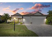 Charming home with a well-manicured lawn, beautiful landscaping, and a three-car garage at sunset at 17045 Polo Trl, Bradenton, FL 34211