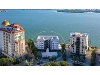 Stunning aerial view of condo building with waterfront views and lush landscaping on a sunny day at 400 Golden Gate Pt # 51 & 52, Sarasota, FL 34236