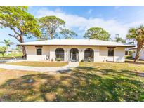 Charming single-story home featuring arched windows, a walkway, mature trees, and well-maintained landscaping at 411 S Oxford Dr # 411, Nokomis, FL 34275