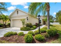 Landscaped front yard featuring a charming one-story home and driveway with an attached garage at 4954 Newport News Cir, Lakewood Ranch, FL 34211