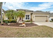 Charming home with a manicured lawn and mature landscaping, including decorative stone and lovely palm trees at 5806 43Rd E Ct, Bradenton, FL 34203
