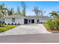 Charming single-story home with a paver driveway and manicured landscaping at 749 Tropical Cir, Sarasota, FL 34242