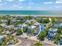 Stunning aerial view of a coastal home near a pristine beach and turquoise waters, surrounded by lush tropical greenery at 785 Jacaranda Rd, Anna Maria, FL 34216