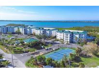 Stunning aerial view of condo community with manicured grounds, tennis courts, and waterfront location with scenic views at 9203 Griggs Rd # A302, Englewood, FL 34224