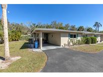 Charming single-story home featuring a carport and well-maintained landscaping under a clear blue sky at 94 Strathmore Blvd, Sarasota, FL 34233