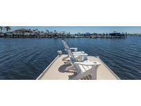 White Adirondack chairs sit at the end of a private dock with panoramic views of the surrounding boats and water at 1009 3Rd E St, Palmetto, FL 34221