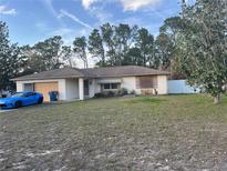 Front exterior of a single story home with a beige exterior and a blue car parked in the driveway at 10443 Keystone St, Spring Hill, FL 34608
