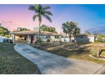 Charming single-story home features a well-maintained lawn and long driveway leading to a covered carport and bright red front door at 2207 Holyoke Ave, Bradenton, FL 34207