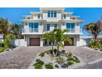 Stunning waterfront home boasting a private brick driveway, mature palms, and dual wooden garage doors at 244 Willow Ave, Anna Maria, FL 34216