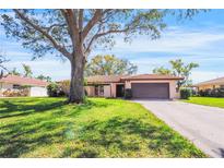 Charming single-story home featuring a lush green lawn, mature trees, and a two-car garage at 314 Signorelli Dr, Nokomis, FL 34275