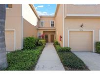Tan townhome featuring a private one car garage and walkway to the front door at 3456 Parkridge Cir # 33-105, Sarasota, FL 34243