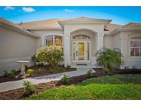 Charming home entrance with arched doorway, lush landscaping and inviting curb appeal at 3528 Monday Ter, North Port, FL 34286