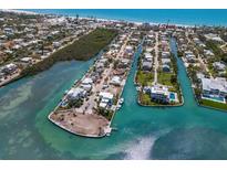 Stunning aerial view of waterfront homes with private docks and boats on a sunny day near a sandy beach at 619 Bayview Dr, Longboat Key, FL 34228