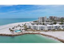 Stunning aerial view of beachfront condos, showcasing the pool, white sands, and turquoise waters at 100 Sands Point Rd # 225, Longboat Key, FL 34228