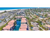 Stunning aerial view of waterfront condos with red roofs, set against a backdrop of beach, ocean, and cityscape at 1113 Lake House Cir # C110, Sarasota, FL 34242