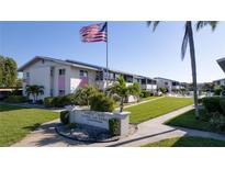 Well-maintained condos with lush landscaping, sign, and American flag on a clear day at 2505 Beneva Rd # 3, Sarasota, FL 34232