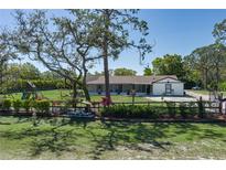 Spacious front yard featuring mature trees, a charming fence, and a glimpse of the home's exterior at 3903 71St E St, Palmetto, FL 34221