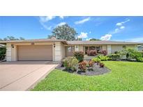 Charming single-story home featuring a well-manicured lawn and vibrant landscaping at 4848 Greywood Ln, Sarasota, FL 34235