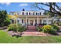 Charming home featuring a brick pathway, lush landscaping, and a welcoming front porch with columns at 813 Hudson Ave, Sarasota, FL 34236