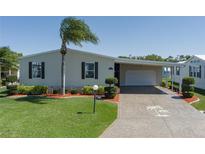 Charming single-story home featuring a carport, well-maintained lawn, and decorative palm tree driveway inlay at 8424 Regal Way, Palmetto, FL 34221
